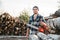 Strong lumberjack wearing plaid shirt hold in hand chainsaw for work on sawmill