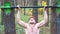 Strong man doing pull ups on horizontal bar with crazy expression on face. Male sportsman exercising at nature. Young