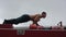 Strong man doing push-up on top of fire truck. Close view