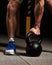 Strong man holding one muscle arm the kettlebell on dark sport c