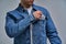 Strong man in jacket standing close-up takes a condom from his denim jacket. Safety concept