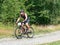 Strong man on light black trekking bike is riding on gravel road