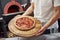 Strong man`s hands. Picture of prepared delicious pizza with sausage rings and olives