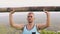 Strong man training press exercise with wooden barbell on tropical hill landscape. Bodybuilder man lifting weight with