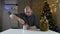 Strong man using opener hands cutting the lid of a metal can on a table with pickles in front of a christmas tree