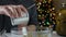 Strong man using opener hands cutting the lid of a metal can on a table with pickles in front of a christmas tree.green