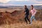 strong man and woman jogging along field outside the city at sunset, runners training