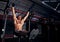 Strong masculine athlete  man doing press exercises hanging on crossbar and lifting the legs up on dark fitness club background.