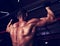 Strong masculine man athlete doing pull ups o dark fitness club background. Closeup