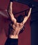 Strong masculine man athlete doing pull ups o dark fitness club background. Closeup portrait