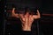 Strong masculine man athlete doing pull ups o dark fitness club background. Closeup portrait