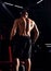 Strong masculine man athlete doing standing in dark fitness club background. Closeup portrait