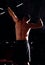 Strong masculine man athlete doing standing and stretching up in dark shadow fitness club background. Closeup portrait