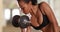 Strong mixed race asian woman doing bicep curls at the gym