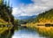 Strong mossy boulders line the edges of the lower Rogue River in late October with blue sky and clouds in distance