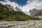 Strong mountain rocky river Adishchala and its source glacier Lardaad on a background on a sunny day