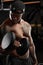 Strong and muscular dark skin man trains on modern equipment in gym. Portrait of muscular pumped up fitness trainer