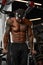 Strong and muscular dark skin man trains on modern equipment in gym. Portrait of muscular pumped up fitness trainer