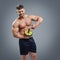 Strong muscular man holding a fitness wheel on grey background