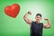 Strong muscular young man showing biceps with big red heart on green background