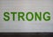 STRONG is painted in bold green letters on a white brick wall in the parking garage on Victory Park Lane, Dallas, Texas