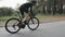 Strong skinny fit cyclist riding a bicycle in the park. High speed cycling uphill out of the saddle. Side follow view. Cycling con
