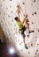 Strong sportsman climbing artificial wall in bouldering gym indoors.