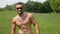 Strong sportsman outdoor, shirtless, looking at camera