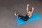 Strong and sporty fitness woman in black sportswear doing abdominal exercises and holding hands up on blue yoga mat at gym. Sport