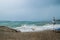 Strong storm, dark cloudy sky, waves and wind at sea, waves washed away beach umbrellas, danger for swimming and surfing