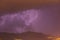 Strong thunder-storm above night mountains and city. Large Bright Lightning Close up. Mediterranian winter night