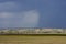 A strong thunderstorm is approaching over a hilly country.