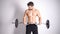 Strong topless man doing exercise with dumbbells