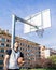 Strong urban basketball player is leaning on the basket column while holding his ball with his left arm