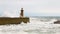 Strong waves break about the pier, the lighthouse on the shore of the Atlantic Ocean