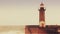 Strong waves break about the pier, the lighthouse on the shore of the Atlantic Ocean