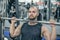 Strong-willed young man fitness model engaged with a barbell in the Smith simulator in the gym. Concept of strong muscles and taut