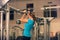 Strong woman in blue t-shirt and black pants exercising in a gym - doing pull-ups.