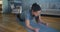 Strong woman stands in plank pose on grey mat in room