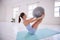 Strong woman training her core with a ball. Young woman using exercise ball in yoga studio. Dedicated using exercise