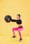 Strong woman workout with med ball. Photo of sporty latin woman in fashionable sportswear on yellow background.