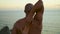 Strong yogi practice spiritual asana at evening ocean closeup. Muscular man back