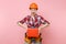 Strong young handyman woman in orange helmet, plaid shirt, denim shorts, kit tools belt full of instruments, toolbox