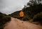 Strong young male athlete completing steep long distance run on gravel mountain path with bushes and trees in cloudy