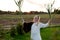 Strong young woman with a bulrush grass reed on rural field background at sunset