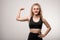 Strong young woman keeping arm bent in elbow while showing her physical strength