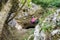 Strong young woman near a cave entrance, during a via ferrata route