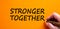 Stronger together symbol. Businessman writing `stronger together`, isolated on orange background. Business, motivational and