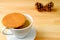Stroopwafel Dutch Cookie Placed on Hot Coffee Cup Served on Wooden Table with Blurred Natural Pine Cones in Background