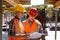 Structural engineer and architect dressed in shirts, orange work vests and helmets explore construction documentation on